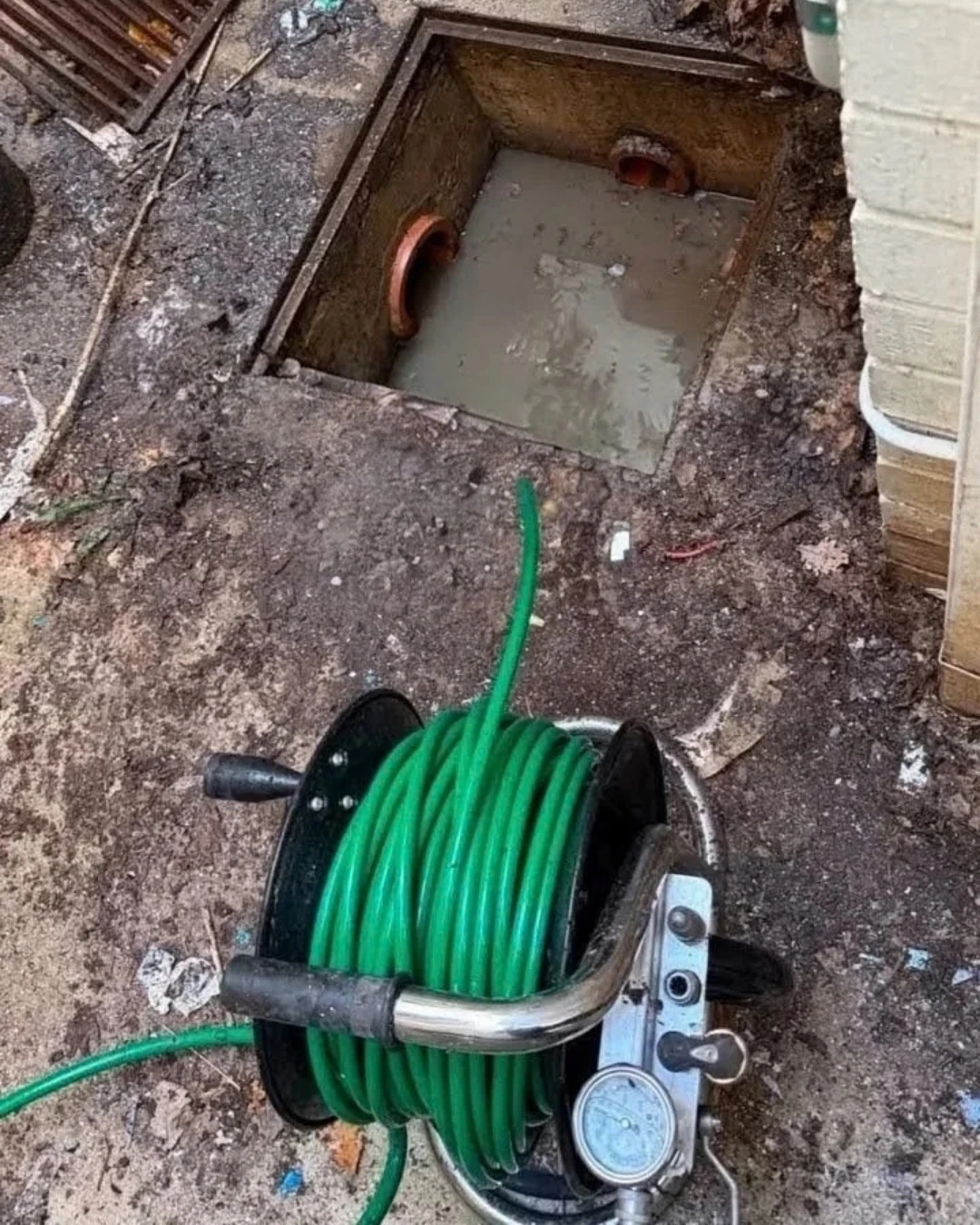 Drain-clearing equipment beside an open commercial stormwater pit in Kingston