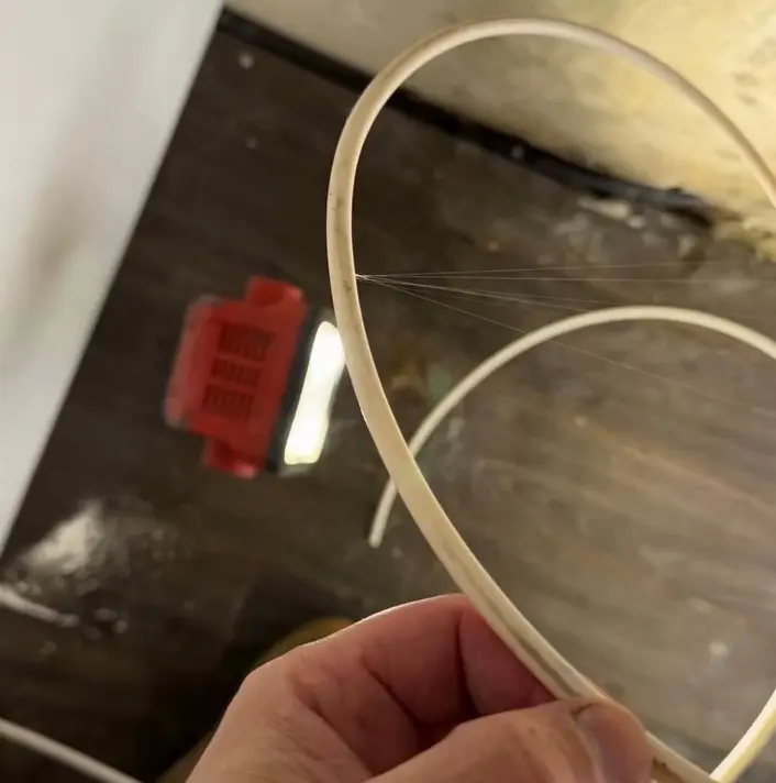 Fine streams of water spraying from a pinhole leak in a fridge water line
